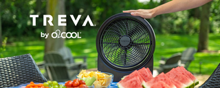 A black Treva by O2Cool fan is shown outdoors on a patio table with watermelon and fruit, with a person's hand resting on the top. The Treva logo and 'by O2Cool' text are visible on the left.